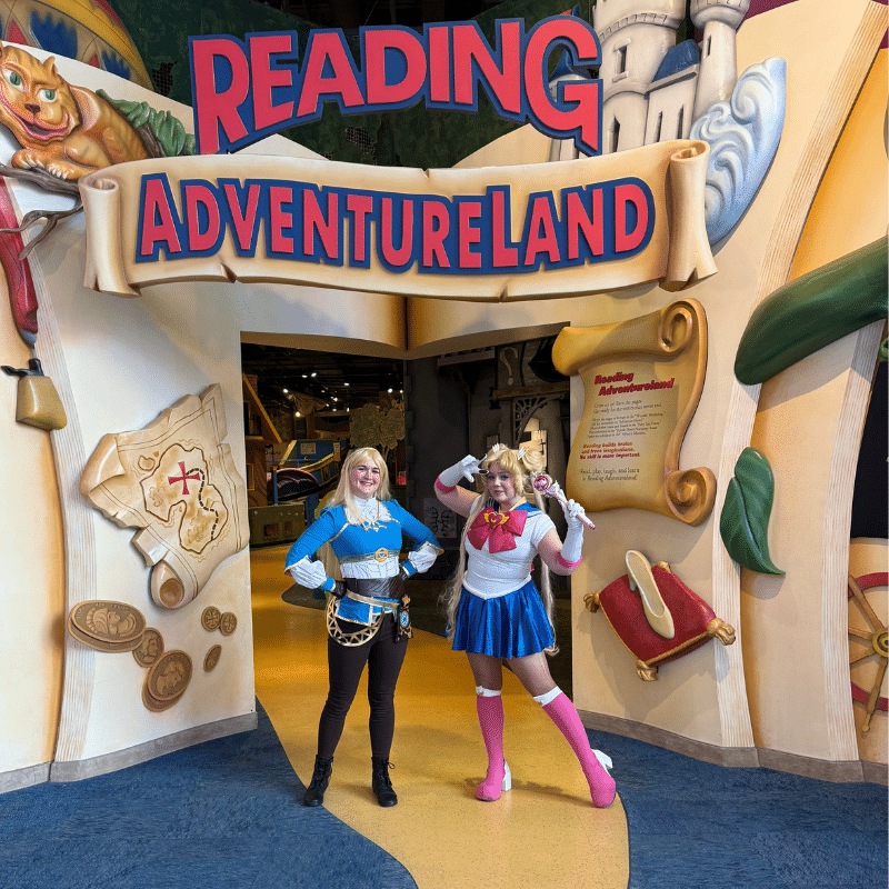 Two people in Anime cosplay standing under the Reading Adventureland sign