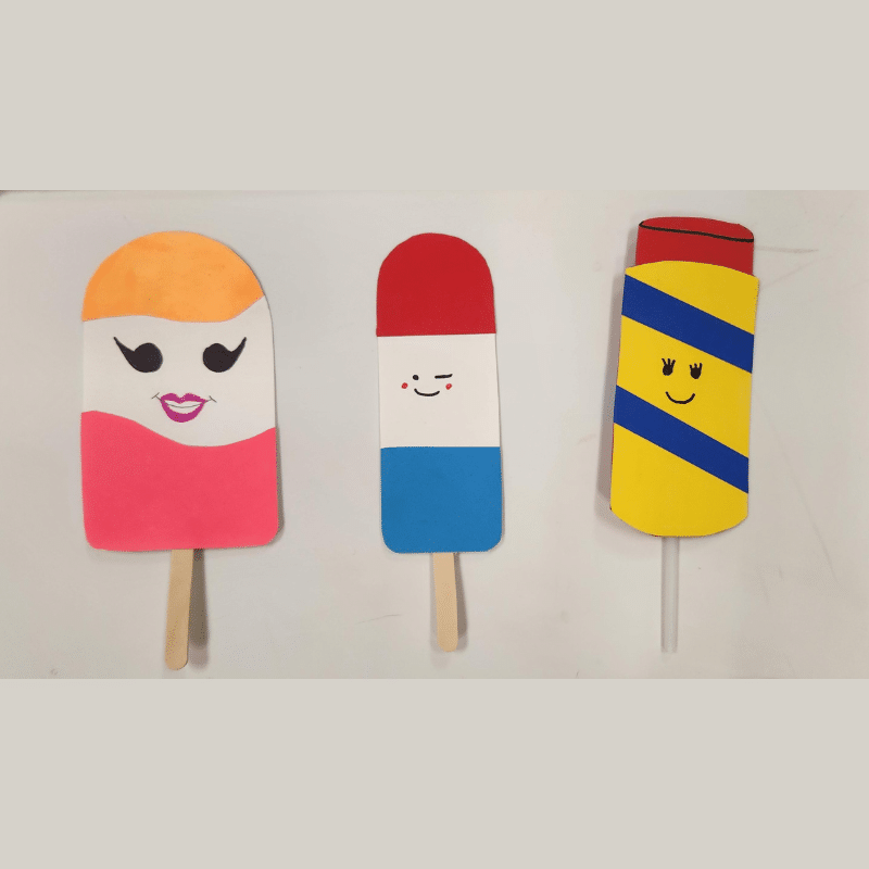 three popsicle crafts with smiling faces.